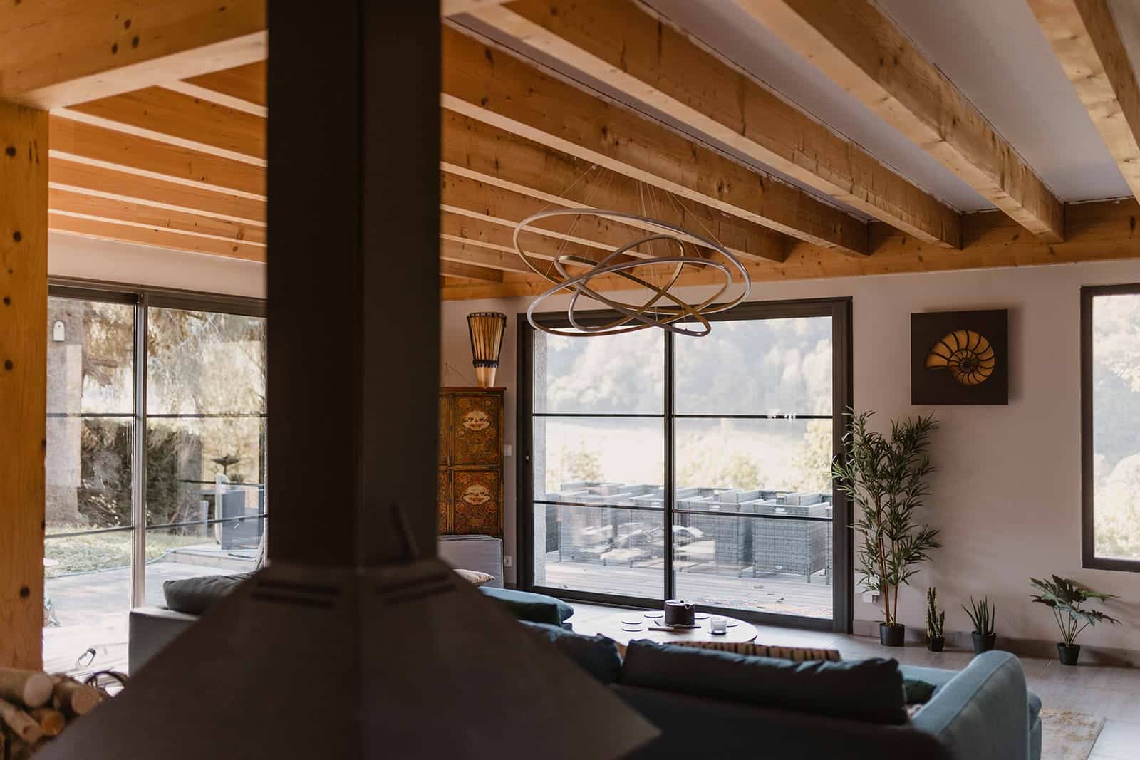 Hébergement - Maison Akasha Yoga Pièce de vie avec cheminée centrale et baie vitrée sur la montagne
