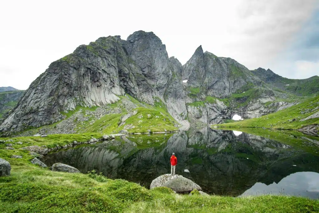 Randonneur au bord d’un lac de montagne – les bienfaits de la randonnée (élément Terre) Randonneur seul au bord d’un lac de montagne, au pied de pics rocheux : les bienfaits de la randonnée en montagne sur le corps et le mental, élément Terre